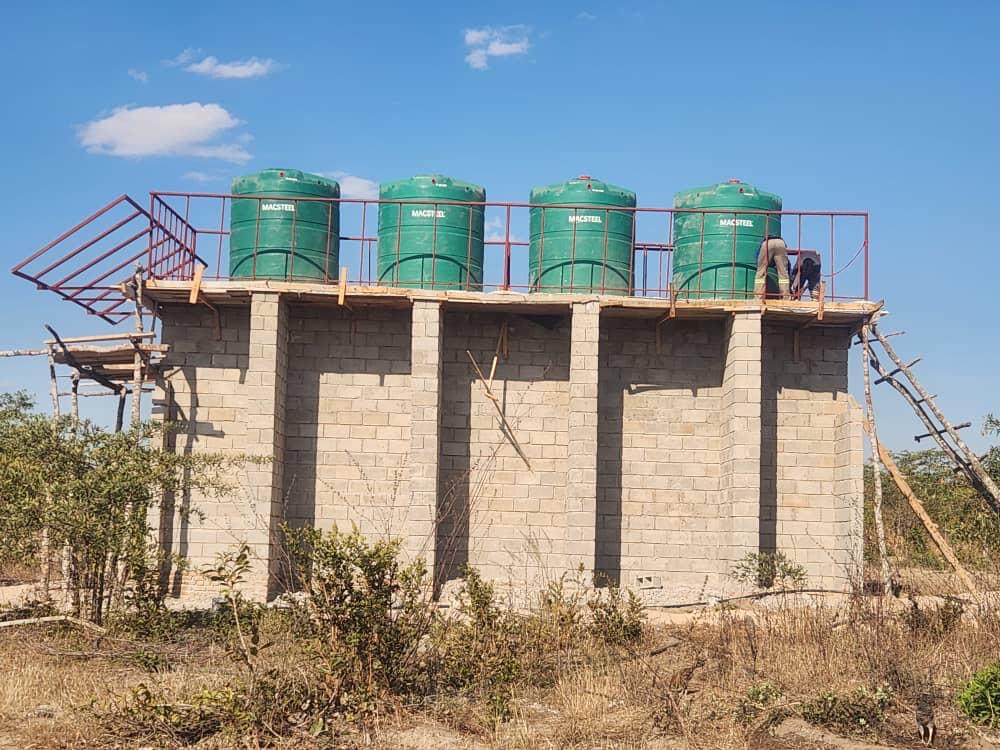 Green plastic water tanks on a high platform with pipes